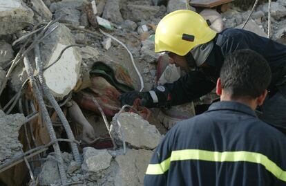 Un trabajador intenta rescatar el cuerpo de una mujer de los escombros de un edificio derribado en Bagdad.
