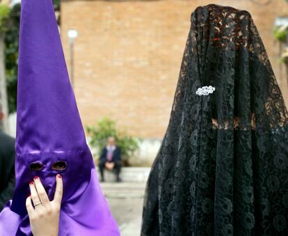 Una mujer con matilla se cruza con una nazarena el Jueves Santo en Sevilla, cuando el viento y la lluvia hicieron imposible procesiones y paseos.