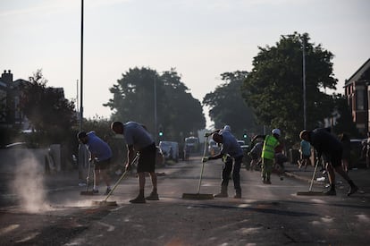 Voluntarios y trabajadores locales barren los escombros de una calle en Southport tras una noche de disturbios violentos, este miércoles. 