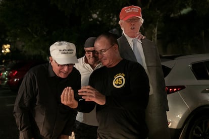 Partidarios del presidente de Estados Unidos, Donald Trump, miran un teléfono mientras esperan a que pase en su caravana, en West Palm Beach, Florida.