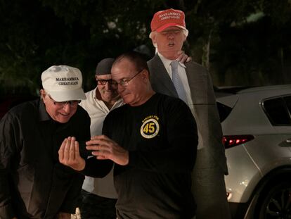 Partidarios del presidente de Estados Unidos, Donald Trump, miran un teléfono mientras esperan a que pase en su caravana, en West Palm Beach, Florida.