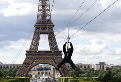 Una joven desciende por una tirolina desde el segundo piso de la Torre Eiffel en París.