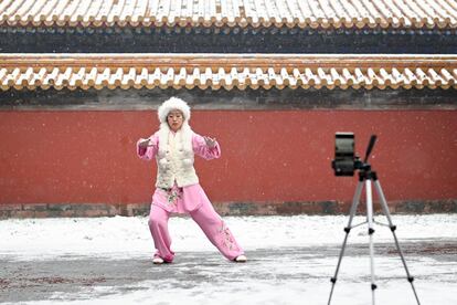 Una mujer se graba practicando tai chi mientras nieva en un parque en Pekín (China).