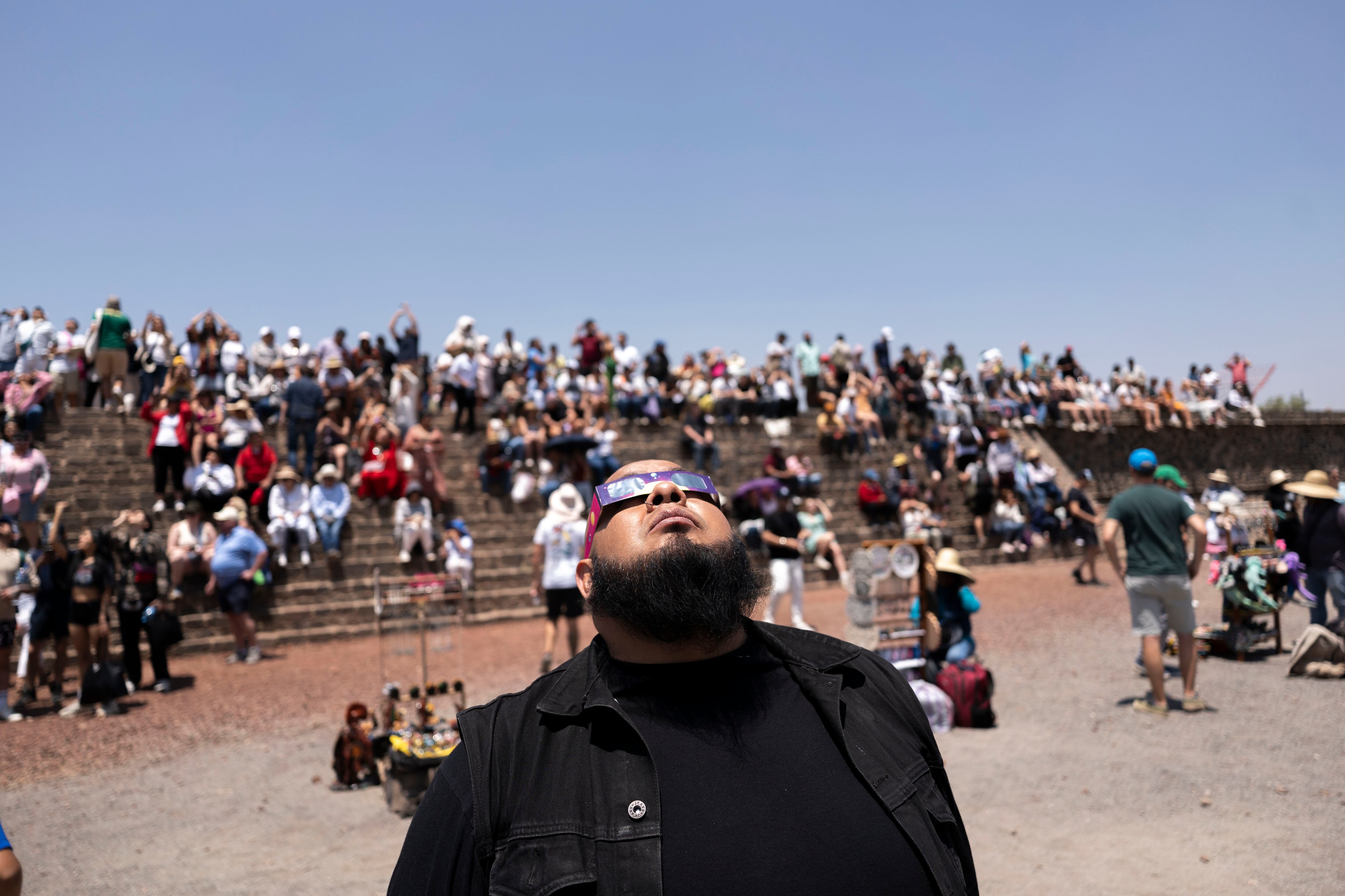 Un hombre observa el eclipse parcial en Teotihuacán (México), mientras una multitud se sienta en las escalinatas de uno de los edificios del antiguo centro ceremonial.