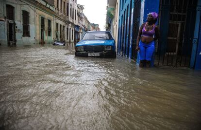 Un mujer rodeada por agua en una calle de La Habana.