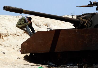 Un rebelde descansa cerca de un tanque destruido en el frente de Bengasi.