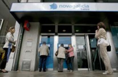 Varias personas esperan para sacar dinero de los cajeros de una sucursal de Novagalicia Banco.