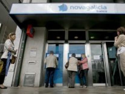 Varias personas esperan para sacar dinero de los cajeros de una sucursal de Novagalicia Banco. 