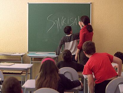 Una profesora ayuda a un alumno en la pizarra.