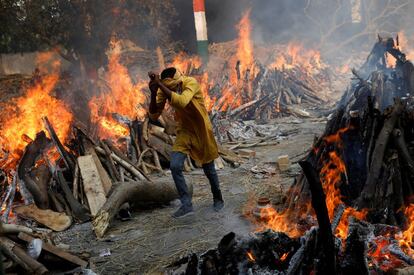 Un hombre camina durante una cremación masiva, en un crematorio en Nueva Delhi, India.