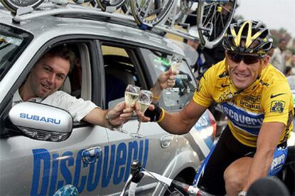 Lance Armstrong brinda con champagne encima de su bici con el director de del Discovery Channel, Johan Bruyneel.