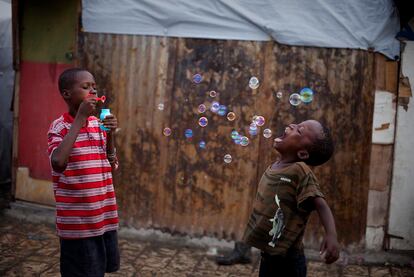 Dos niños juegan con burbujas de jabón en el campo de refugiados donde viven conjuntamente con otras personas afectadas por el terremoto del 12 de enero de 2010 en Port-au-Prince, Haití. 29 de septiembre de 2010.