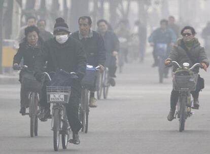 Ciudadanos chinos circulan en bicicleta por una avenida de Pekín.