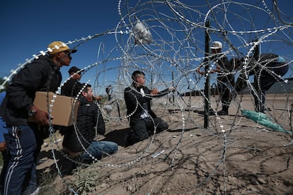 Un grupo de migrantes cruzan una valla de alambre de espinas desde Ciudad Juárez (México) hacía Estados Unidos, este martes.  