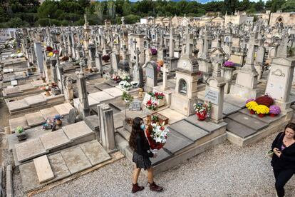 Una mujer deposita flores  en el cementerio de Palma de Mallorca.