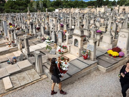 Una mujer deposita flores  en el cementerio de Palma de Mallorca.