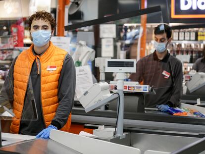 Adrián, 21, estudiante y empleado de un supermercado Día & Go en Madrid posa junto a las cajas.