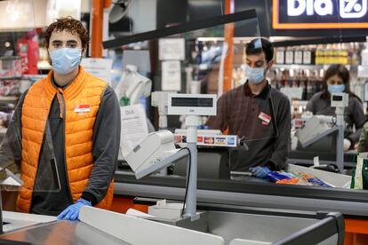 Adrián, 21, estudiante y empleado de un supermercado Día & Go en Madrid posa junto a las cajas.