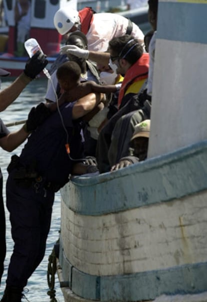 Un policía ayuda a desembarcar del pesquero a un niño de año y medio.