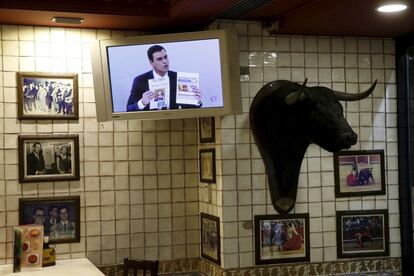 Un televisor de un restaurante en Madrid muestra al líder del PSOE Pedro Sánchez con la portada del diario El País