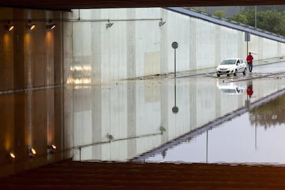 Una persona observa un puente anegado de Málaga por las fuertes lluvias caídas esta noche en la capital.