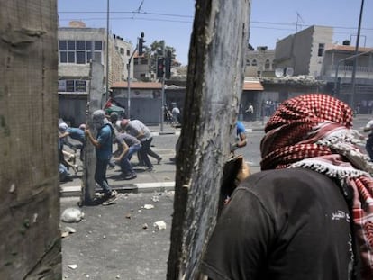 Jóvenes palestinos lanzan piedras a las fuerzas de seguridad israelíes en los disturbios tras el funeral del joven palestino asesinado. 