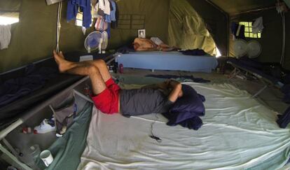 Hombre tumbado en una cama junto a ventiladores en una tienda en el centro de detención de Nauru.