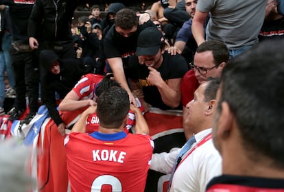 Los jugadores del Atlético de Madrid, Koke y José María Giménez, hablan con los fans para que dejen de lanzar objetos al campo, el domingo.