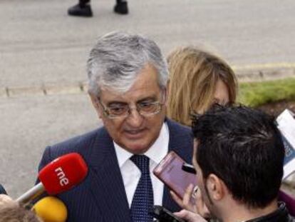 El fiscal general del Estado, Eduardo Torres Dulce realiza unas declraciones a los medios, mientras un policia nacional controla a un afectado por las preferentes, momentos antes de intervenir en la entrega de los XVI Premios Europeos de la Arquitectura Técnica a la Seguridad en la Construcción.