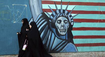 Imagen de archivo que muestra a dos mujeres iraníes frente a un muro con un grafiti contra EEUU.
