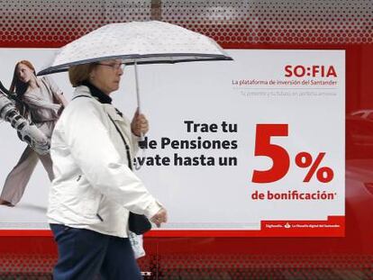 Una mujer pasa delante de una sucursal donde se anuncian planes de pensiones.