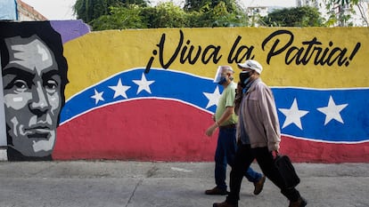 Dois homens passam em frente a um cartaz de Caracas, neste domingo.