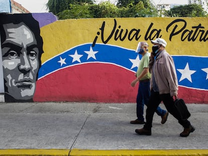 Dos hombres pasan por delante de un cartel en Caracas, este domingo.