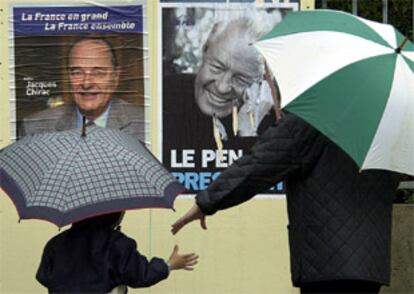 Ciudadanos franceses observan los carteles electorales de Jacques Chirac y Jean-Marie le Pen,un día antes de la seguna vuelta de las presidenciales francesas.