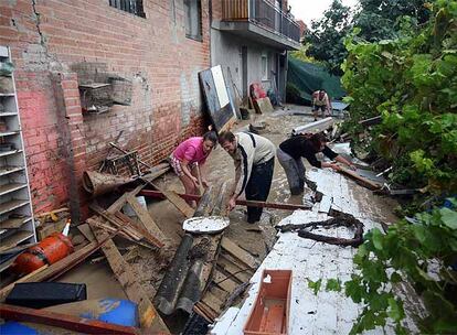 Unos vecinos de Coslada, durante las labores de limpieza de las traseras de su casas, donde el agua se ha llevado por delante un muro. Los daños materiales son muchos pero están todavía por cuantificar.