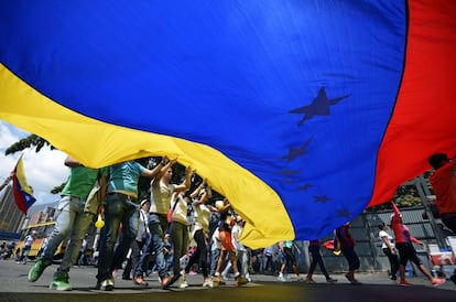 Manifestantes de la oposición ondean una bandera nacional gigante durante una protesta contra el gobierno de Nicolás Maduro para mantener la presión en las calles de Caracas la víspera del aniversario de la muerte de Hugo Chávez. Al menos 18 personas han muerto y más de 200 han resultado heridas desde qeu comenzasen las protestas a principios de febrero.