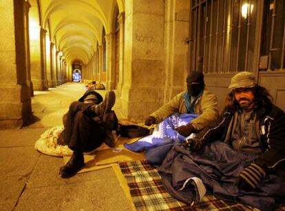 El Duende (a la izquierda) y otros dos indigentes combaten el frío en los soportales de la plaza Mayor.