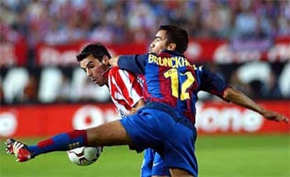 El jugador del Atlético Novo (izqda.) y Van Bronckhorst, del Barcelona, pugnan por el balón en el partido disputado en el Vicente Calderón.