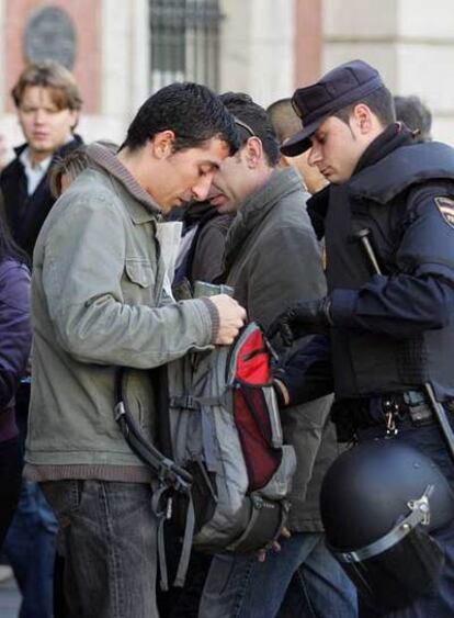 Un policía registra a un joven en la concentración.