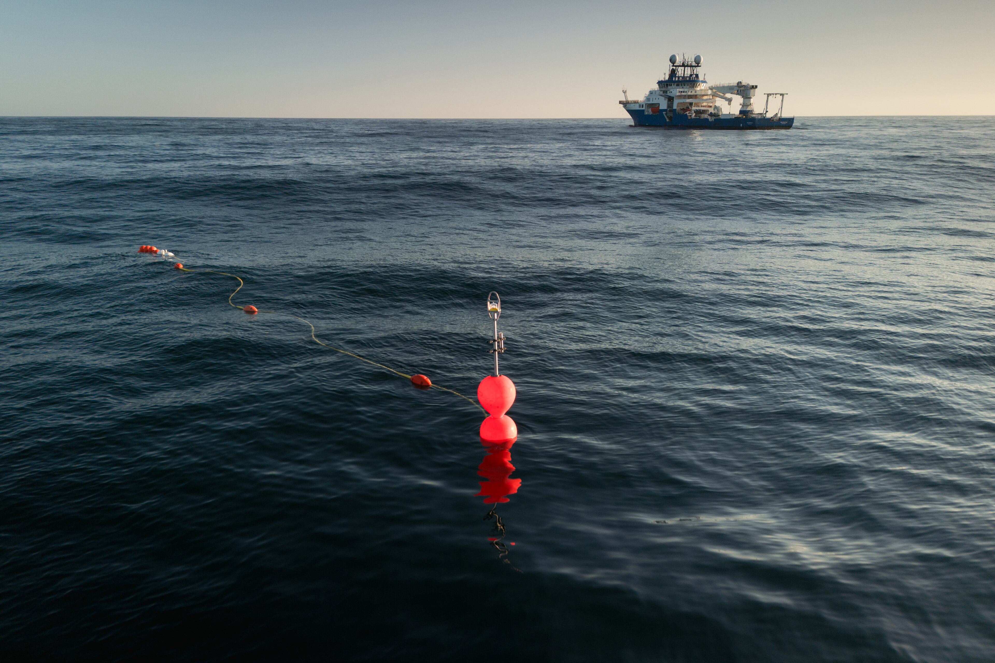 Unas boyas luminosas conectadas a equipos sumergidos flotan en la superficie del océano.