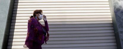 Una persona con mascarilla pasa frente a un comercio.