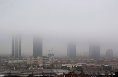 Vista de las Cuatro Torres de Madrid cubiertas por la niebla esta mañana.