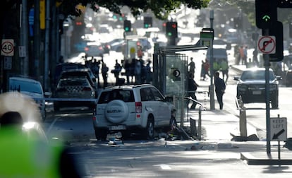 Imagen de un todoterreno blanco empotrado contra una parada de autobús mientras agentes de emergencias llevan a cabo su investigación.