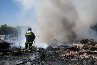 Un bombero sofoca el fuego en un vertedero cercano al poblado chabolista de Santa Catalina.