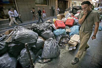 Un hombre cruza frente a unos montones de basuras hoy en Almería.