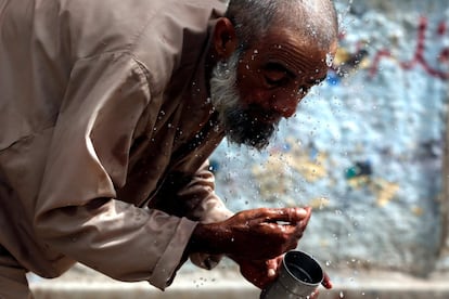 Un hombre se lava la cara con agua en una carretera de Karachi (Pakistán).