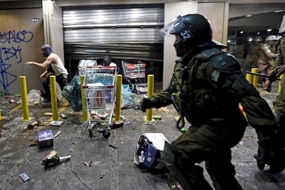 Un policía intenta frenar los saqueos que se presentaron al término de la protesta.