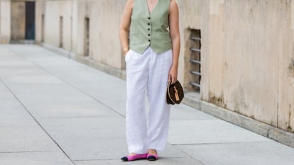Una chica en la calle con un chaleco de tirantes y unos pantalones de lino.
