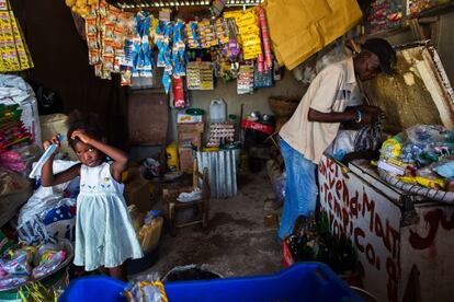 La mayoría de negocios que existen en los campamentos en Haití son de alimentación. También es necesario comprar el agua ya que es difícil encontrarla potable. En esta imagen, una niña se peina –también les gusta estar guapos– mientras su padre extrae unos refrescos del congelador en el negocio familiar que tienen en la comunidad de Onaville, en Canaan, el campamento de desplazados por el terremoto más grande del país. El 76% de la población gana menos de 2,5 dólares al día, por lo que vivir en condiciones dignas es muy complicado.