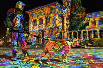 Un hombre y su perro pasean justo durante la proyección 'Buceando en un mar de colores' obra del artista alemán Daniel Margraf en el Palacio Rumine de la Plaza de Riponne durante el festival de las luces de Lausana (Suiza).